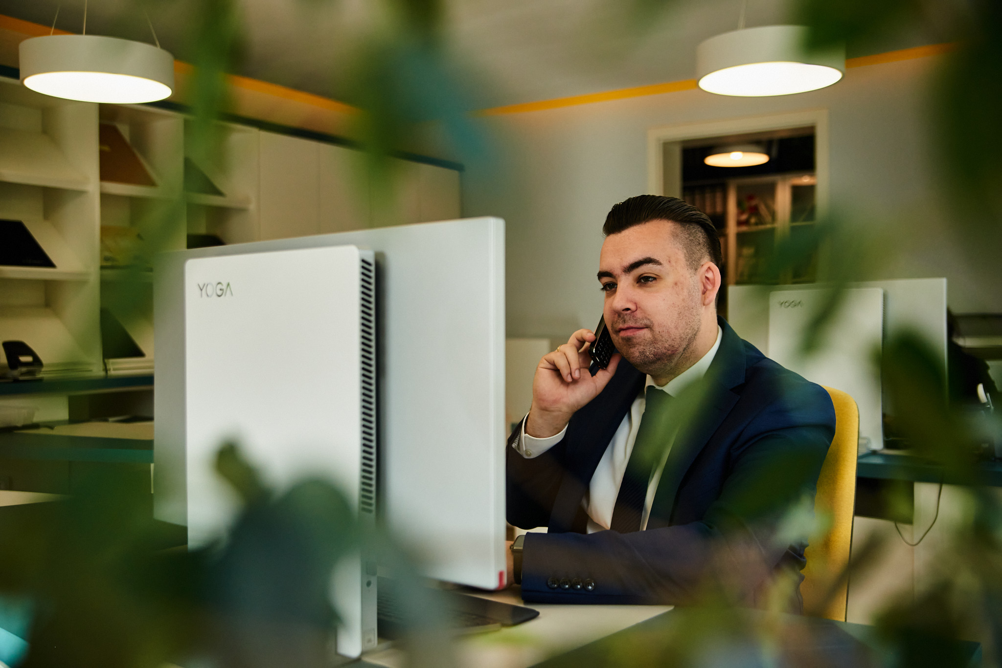 Ein dunkelhaariger Mann im Anzug telefoniert konzentriert im modernen Büro