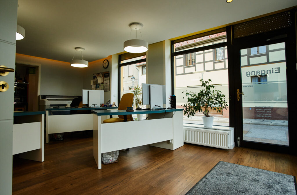 Helles modernes Büro mit weißen Möbeln, großen Fenstern und Holzboden